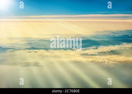 View from a plane to sunset on the sky with sunrays. Sunbeams shining through clouds Stock Photo