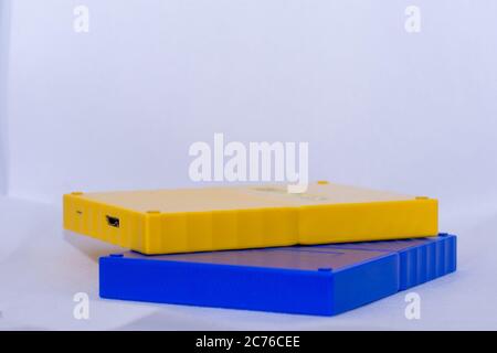 Yellow and blue portable usb hard drives stacked on isolated white background. Stock Photo