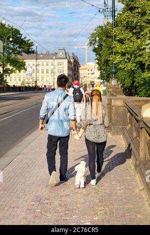 Prague, Czech Republic - June 12, 2014: Couple walks small white dog on a street of Prague. Stock Photo