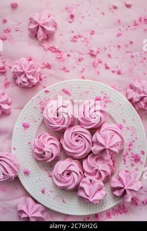 Pink meringues on plate, colorful background, top view Stock Photo