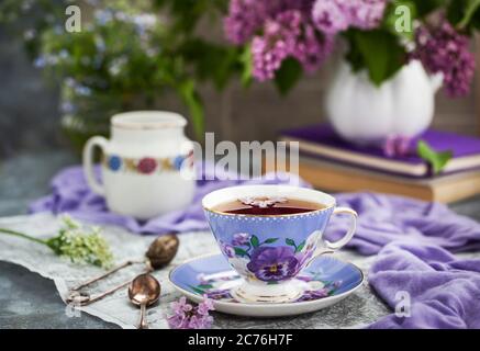 Purple cup of tae and lilac on gray background Stock Photo