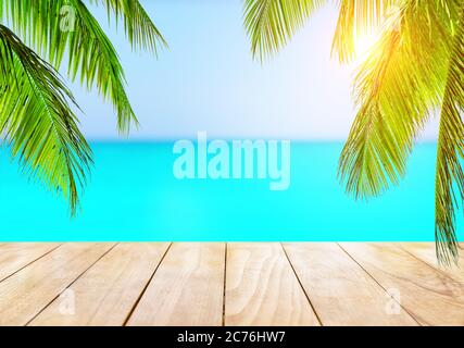 Blurred blue sky and sea with bokeh light and wooden table background. Coconut palm trees against blue sky and beautiful beach in Punta Cana, Dominica Stock Photo