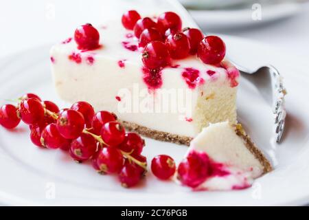 Red currant cheesecake on plate with fork. Selective focus Stock Photo