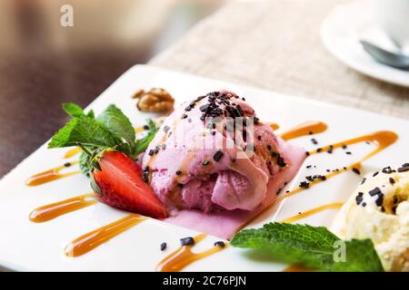 Scoop of strawberry ice cream in bowl in cafe Stock Photo