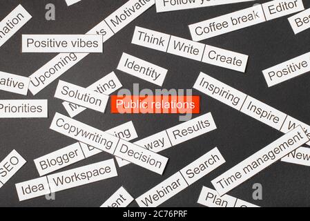 Cut paper inscription public relations on a red background, surrounded by other inscriptions on a dark background. Word cloud concept Stock Photo