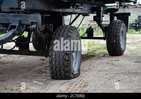 Old rusty tractor's flat back tire. Stock Photo