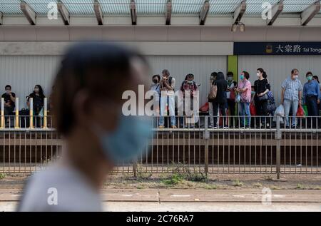 Hong Kong, China. 27th Mar, 2020. People queuing at the light railway while wearing face masks during the coronavirus pandemic.Government has tightened social distancing measure as the city reports 52 (one of the highest daily) new cases of coronavirus. Credit: May James/SOPA Images/ZUMA Wire/Alamy Live News Stock Photo
