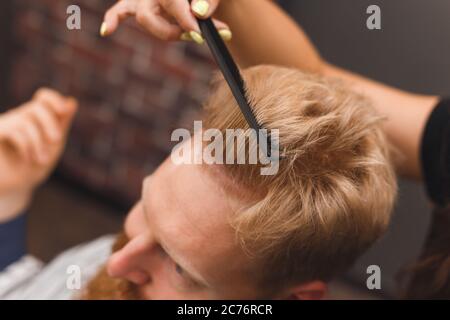 Hairdresser combs hair of handsome client before haircut in barbershop Stock Photo