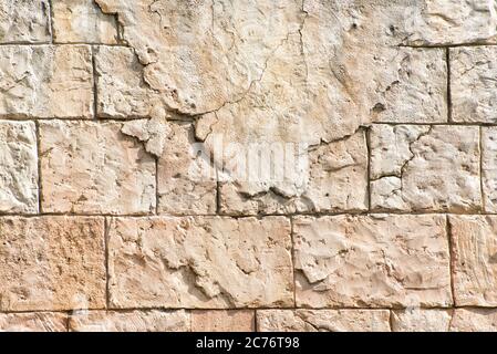 Old gray wall of rectangular stone blocks with remnants of plaster. Abstract background. Stock Photo