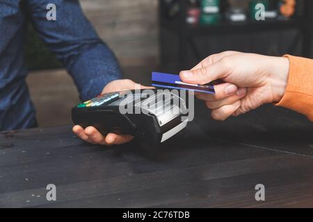 Close-up on hands. Man paying for order with credit card NFC technology using bank terminal Stock Photo