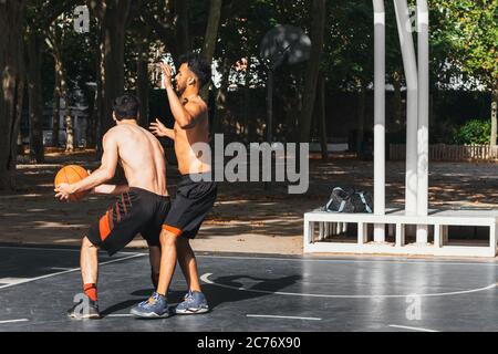 two young men playing basketball outdoors Stock Photo