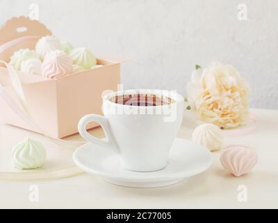 Pastel romantic background with coffee and small meringues in a box, flower and ribbons. Stock Photo