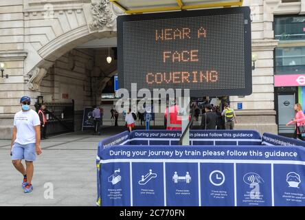 Westminster, London, UK. 14th July, 2020. A large sign and dedicated staff remind commuters to wear a face covering at Victoria Train Station. Face masks ar already mandatory on public transport, and a also required in shops and supermarkets from July 24th in England. Credit: Imageplotter/Alamy Live News Stock Photo