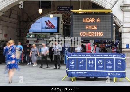Westminster, London, UK. 14th July, 2020. A large sign and dedicated staff remind commuters to wear a face covering at Victoria Train Station. Face masks ar already mandatory on public transport, and a also required in shops and supermarkets from July 24th in England. Credit: Imageplotter/Alamy Live News Stock Photo