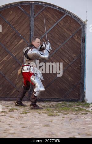 Knight infantryman in armor and with a sword shows combat strikes. Stock Photo