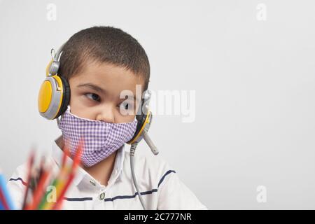 Young kid in headphones doing online exercises via laptop. Learning foreign language online or distance education, e-learning concepts Stock Photo