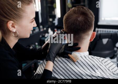 Backside of a man in Barbershop, cutting by barber girl