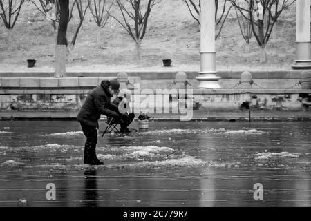 Tianjin, China - Jan 16 2020: Unidentified people ice fishing in the middle of a frosty river Haihe Stock Photo