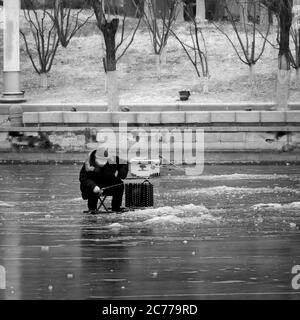 Tianjin, China - Jan 16 2020: Unidentified people ice fishing in the middle of a frosty river Haihe Stock Photo