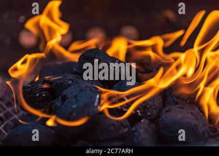 Grill briquettes that are burning and waiting to be glowed for grilling, Briquettes are made from lignite, peat, charcoal or coal stub Stock Photo