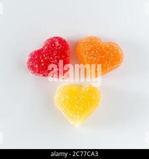 Three multi-colored heart-shaped marmalade on a white background. Symbol of multinational love. Stock Photo
