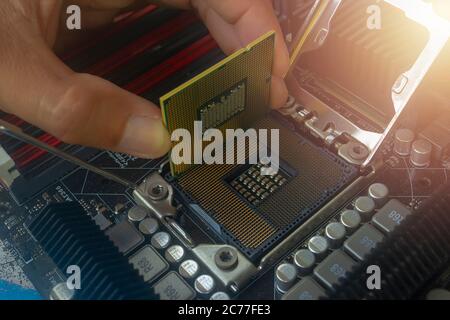 Close up hand of technician putting CPU on the socket of computer motherboard Stock Photo