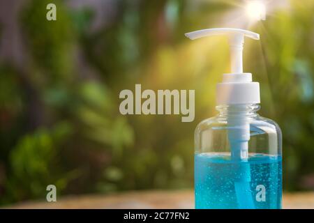 Close up pump of Blue alcohols gel bottle on blur green nature background and sun ray.Hand sanitizer gel in pump bottle. With copy space for text or d Stock Photo