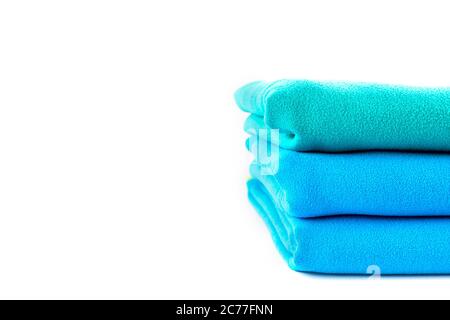 Close up half stack towels green and blue on white background with copy space. Stock Photo