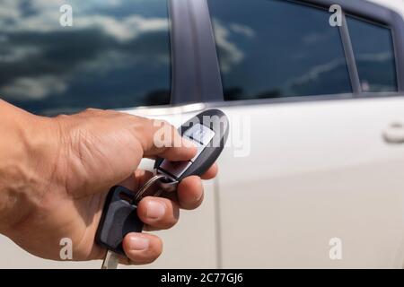 Hand man hold button unlock on the car remote control for unlock door white car. Stock Photo