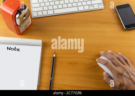 Top view office desk with mouse, laptop, keyboard, bill book, pencil sharpener and pencil on wood table . With copy space for text or design. Stock Photo