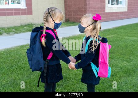 Safety back to school concept, wearing mask for students. Two young sisters going to school. Friendship, family. Stock Photo