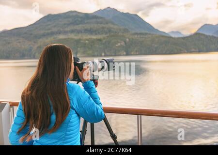 Travel photographer with professional telephoto lens camera on tripod shooting wildlife in Alaska, USA. Scenic cruising inside passage cruise tourist Stock Photo