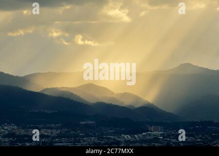 Diagonal sunrays falling down over a hill Stock Photo
