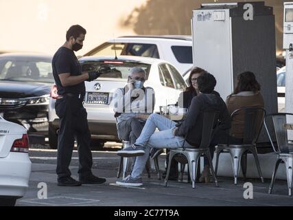 Burlingame, United States. 15th July, 2020. A masked and gloved waiter delivers a bill to customers seated on the sidewalk outside Limon Rotisserie in Burlingame, California on Tuesday, July 14, 2020. California's Governor Gavin Newsom has ordered a rollback in openings and an end to inside dining amid a spike in COVID-19 cases across the state. Photo by Terry Schmitt/UPI Credit: UPI/Alamy Live News Stock Photo