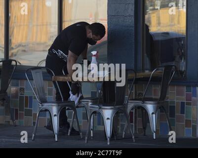 Burlingame, United States. 15th July, 2020. Staff disinfects surfaces betrween customers at sidewalk seating outside Limon Rotisserie in Burlingame, California on Tuesday, July 14, 2020. California's Governor Gavin Newsom has ordered a rollback in openings and an end to inside dining amid a spike in COVID-19 cases across the state. Photo by Terry Schmitt/UPI Credit: UPI/Alamy Live News Stock Photo
