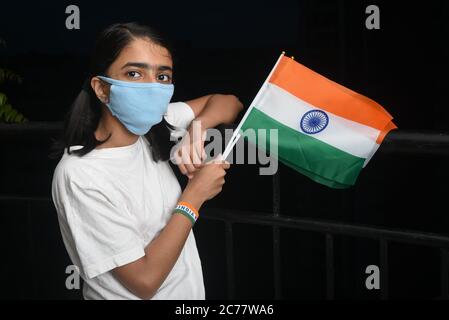 Kerala, India. July 13, 2020.Corona virus pandemic or COVID-19 in India. Young girl holding Indian flag wearing safety mask. Stock Photo