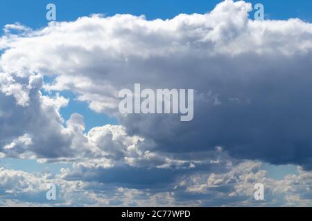 Bright blue sky with cumulus clouds lit by the daytime sun. Abstract background for design. Stock Photo