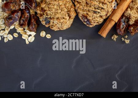 Date and oatmeal cookies and ingredients.  Flat lay, top view on dark slate. Stock Photo