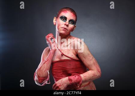 Photo of young girl in fake blood on grey background