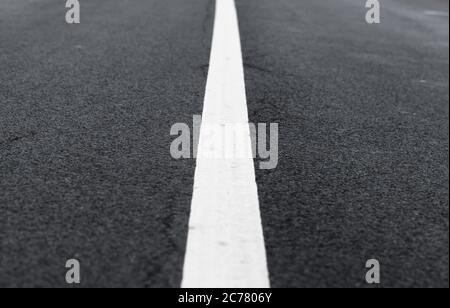 White dividing line perspective over dark asphalt, highway road marking. Abstract transportation background texture Stock Photo