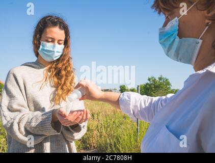 Social distance. Mother pours her daughter disinfectant gel to wash her hands. Mother and daughter in social distancing. Washing their hands. Pandemic Stock Photo