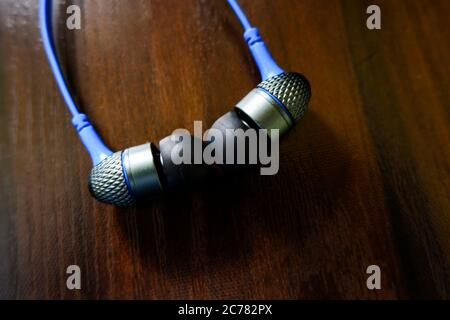 a closeup view of headphone earbuds isolated on wooden texture table Stock Photo