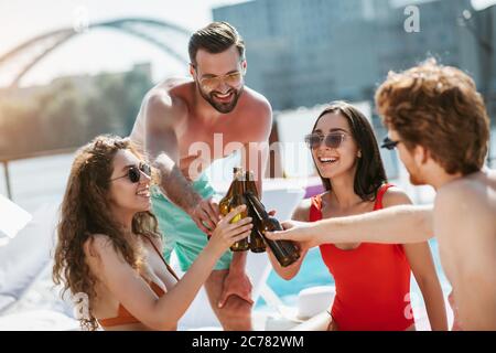 Young people having great time in the swimming pool and having beer Stock Photo