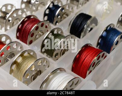 metal bobbins with multi-colored threads in a plastic box Stock Photo