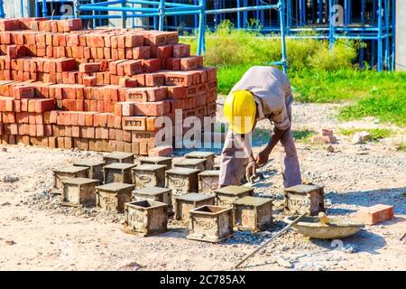 Karnal, Haryana, India - march 2018 : man making up of bricks near the big buildings in karnal Stock Photo