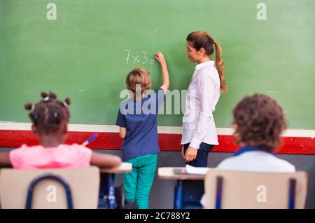 School teacher interviewing pupil at chalkboard. Back to school concept.. Stock Photo