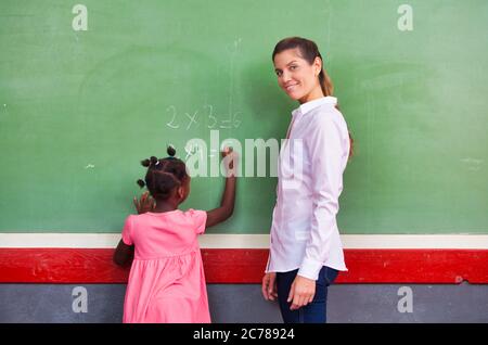 School teacher interviewing pupil at chalkboard. Back to school concept.. Stock Photo
