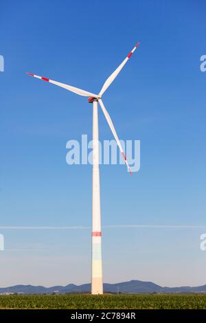 Windmill in front of a landscape with hills producing green electricity - blue sky Stock Photo