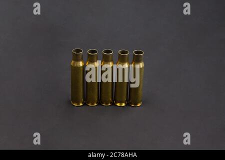 Five empty cartridge cases are lined up side by side. With black background. Stock Photo