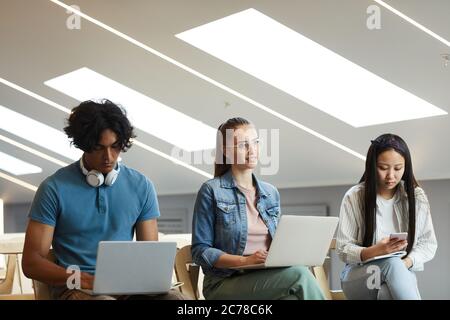 Group of young multi-ethnic students sitting with devices in row at university lecture Stock Photo